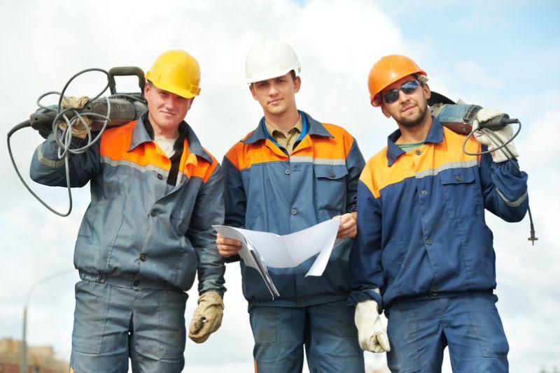 3 construction workers posing with their equipment