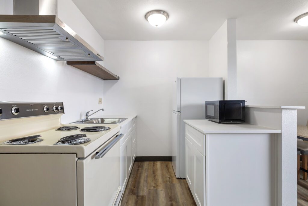 In-room kitchen at Kennewick Inn & Suites Tri Cities with a stove, sink, refrigerator, and microwave.