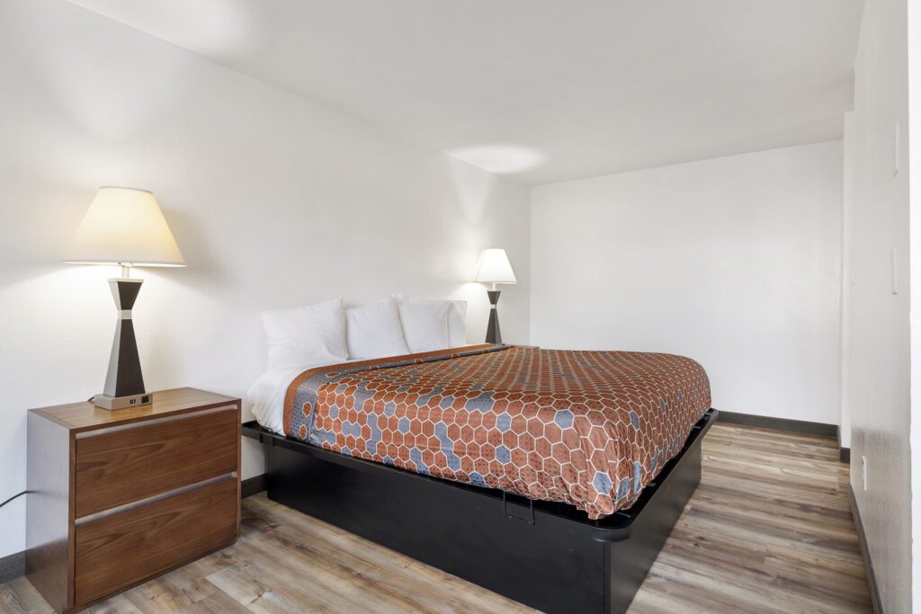 Hotel room at Kennewick Inn & Suites Tri Cities with one king bed, nightstands, and lamps.