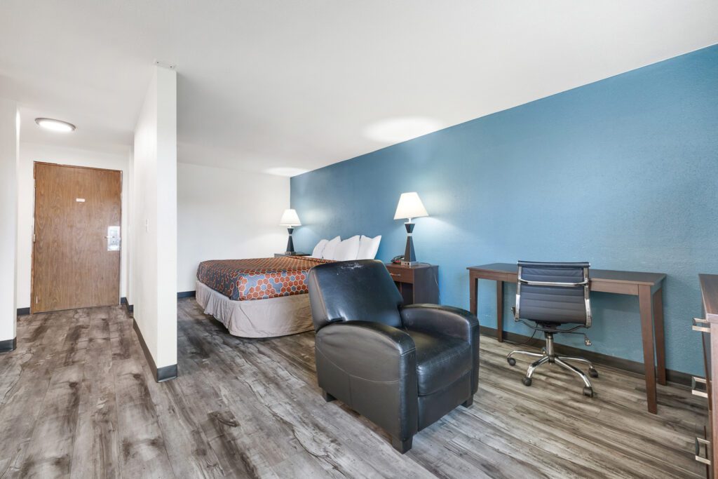 Hotel room with one king bed, reclining chair, work desk, work chair and dresser at Kennewick Inn & Suites Tri Cities.