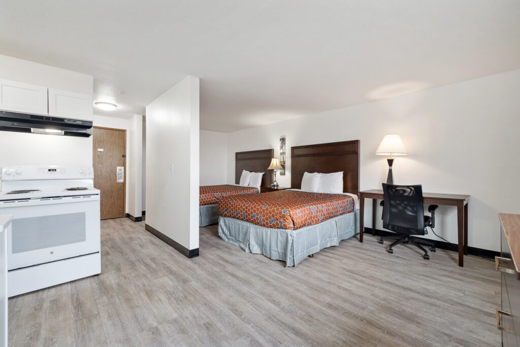 Hotel room with two queen beds, workspace, and in-room kitchen at Kennewick Inn & Suites Tri Cities.