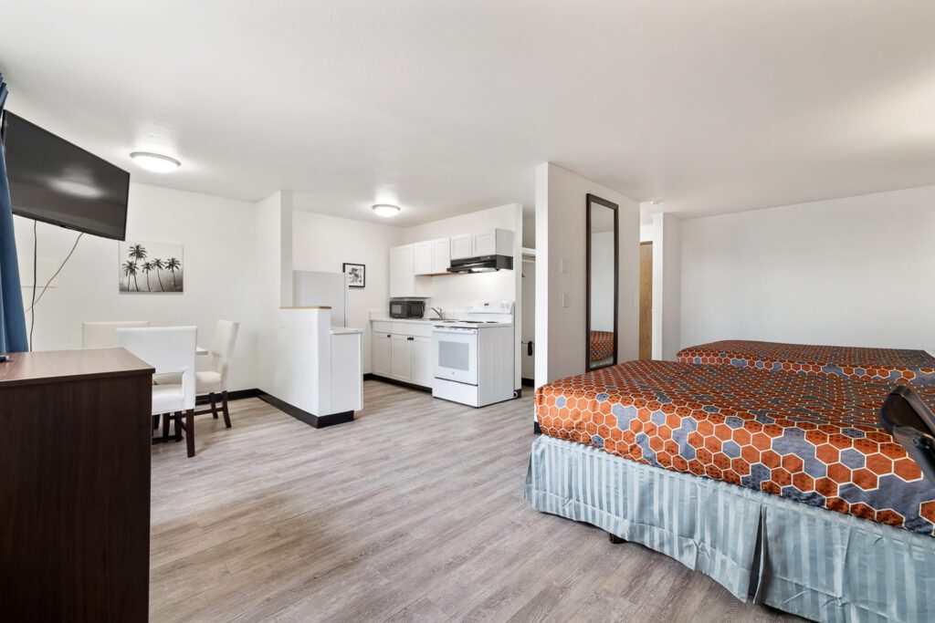 Hotel room with two queen beds, dining table, TV, and in-room kitchen at Kennewick Inn & Suites Tri Cities.