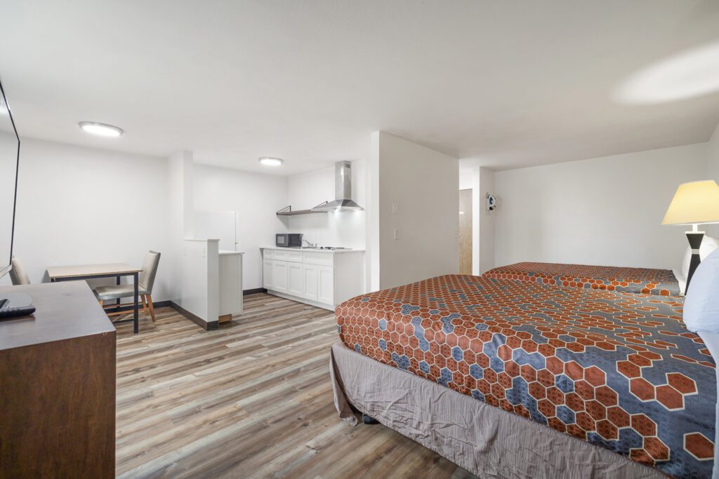 Hotel room with two queen beds, dining table, dresser, and in-room kitchen at Kennewick Inn & Suites Tri Cities.